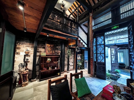 A spacious interior with a high ceiling, wooden beams, a staircase, and a view of the outside.. Dream Country Qiankou Resort