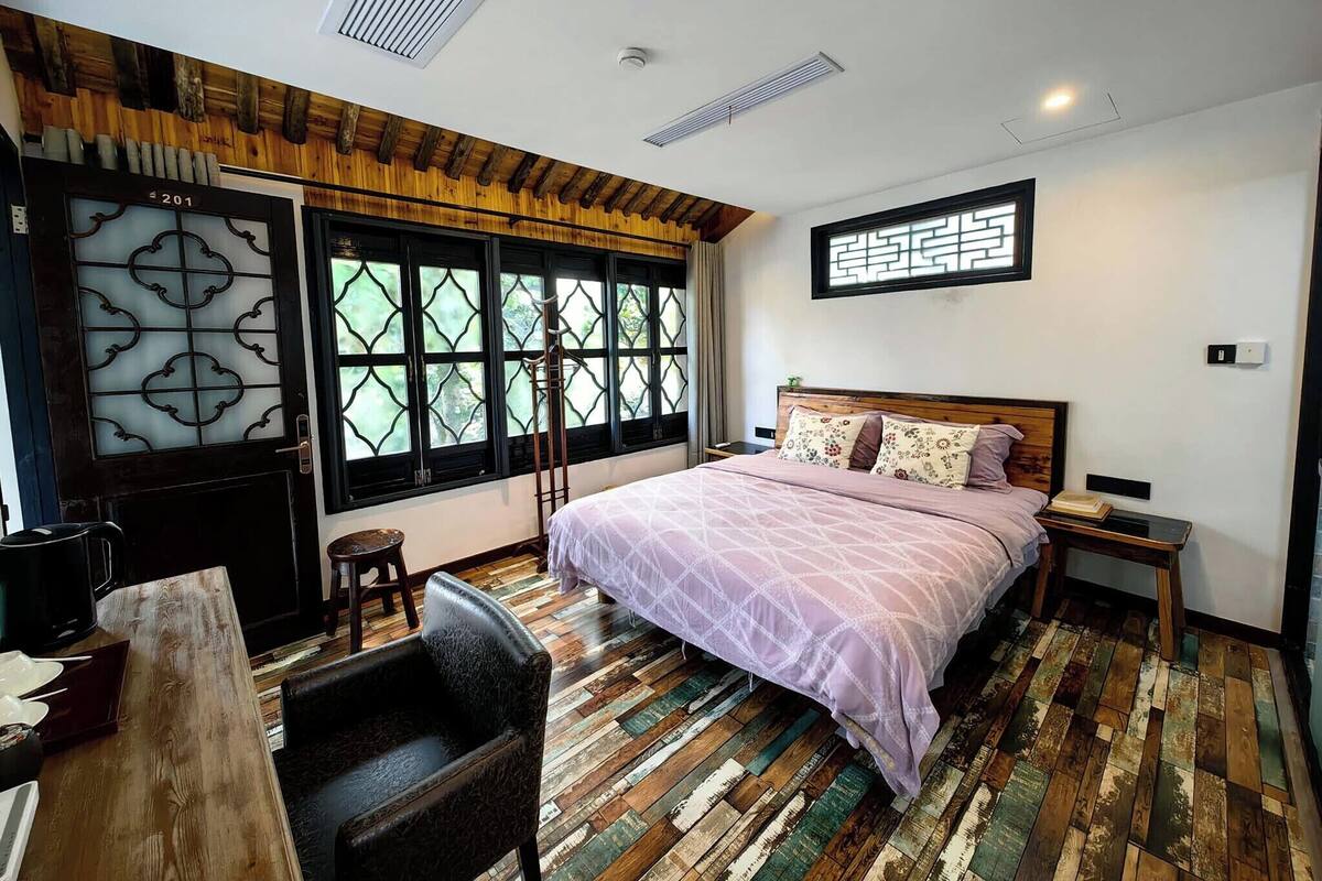 A bedroom with a bed, a desk, and a chair.