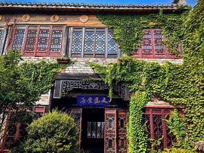 Um edifício tradicional com fachada de madeira, várias janelas com desenhos de treliça elaborados e uma placa com caracteres chineses.