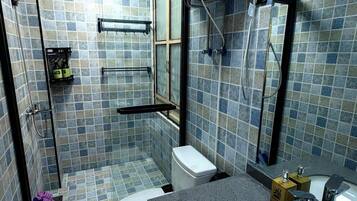 A bathroom with a shower, toilet, and sink, tiled in blue and gray.