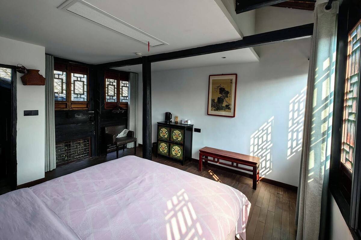 A room with a bed, a wooden bench, a cabinet, and a traditional painting on the wall.