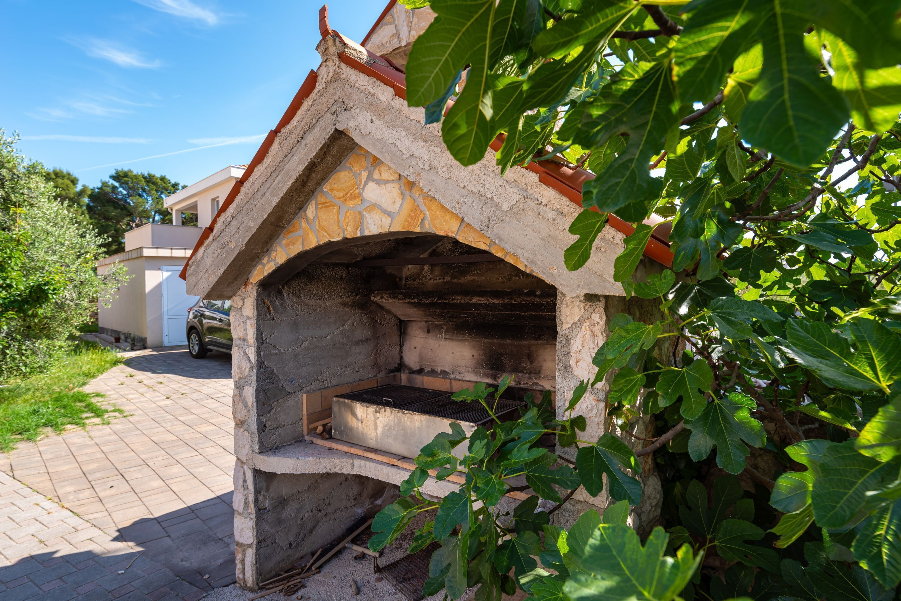 Estructura de horno de piedra con techo de ladrillo, rodeada de follaje.