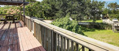 A wooden deck with a picnic table, surrounded by lush greenery and trees.