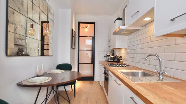 A compact kitchen with a wooden countertop, white cabinets, and a dining area with a table and chairs.