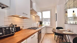 A modern kitchen with white cabinetry, a wooden countertop, and a dining area with a table and chairs.
