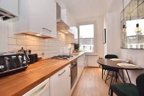 Una cocina moderna con armarios blancos, encimera de madera y zona de comedor con mesa y sillas.