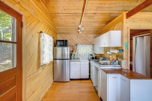 A compact kitchen with wooden walls, a stainless steel refrigerator, a microwave, and a sink. - Waterfront Berkshires Studio w/ Dock on Goose Pond (Lee)