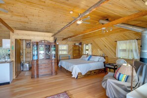 Interior de una cabaña de madera con cama, cómoda y zona de comedor.