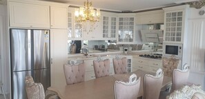 A kitchen with white cabinetry, a stainless steel refrigerator, a chandelier, and a dining table with chairs. - King's apartment 10 min to Konyaalti beach (Muratpaşa)