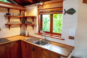 Eine Küche mit Holzböden, einem Spülbecken und einem Fenster mit Blick auf Grünflächen.