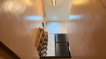 A kitchen with a refrigerator and a hanging light fixture.