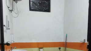 Un baño pequeño con lavamanos, dos inodoros, una ventana y un trapeador.