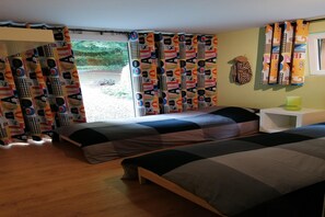 A room with two beds, a white nightstand, a green cup, and a window with curtains. - Les Rainettes – Quiet family home with garden and terrace in the Ardennes (Grand-Halleux)