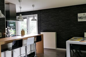 A modern kitchen with a central island, pendant lighting, and a view of the outdoors. - Les Rainettes – Quiet family home with garden and terrace in the Ardennes (Grand-Halleux)