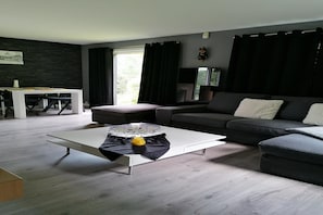 Un salon moderne comprenant un canapé, une table basse et un coin repas avec une table et des chaises.