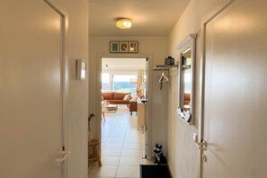 A hallway leading to a living area with a sofa, a coffee table, and a view of the outdoors. - Sunny-side apartment in Nieuwpoort (NIEUWPOORT)
