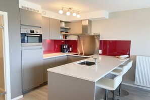 Et moderne køkken med indbyggede apparater, en central ø og barstole.