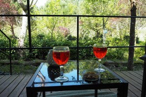 A table with two wine glasses and a bottle, set against a backdrop of greenery and trees. - Tuscan Mobile Home with Veranda (Capannole)