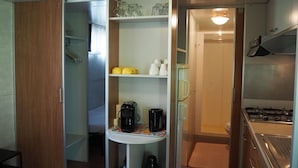 Uma cozinha compacta com fogão, cafeteira e prateleiras com utensílios de cozinha.