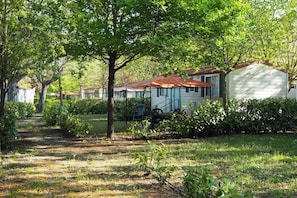 A row of single-story houses with a pathway leading through a garden. - Tuscan Mobile home with Covered Porch (Capannole)
