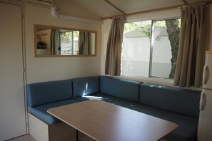Ein gemütlicher Raum mit Sofa, Tisch, Spiegel und einem fenster mit Vorhängen.