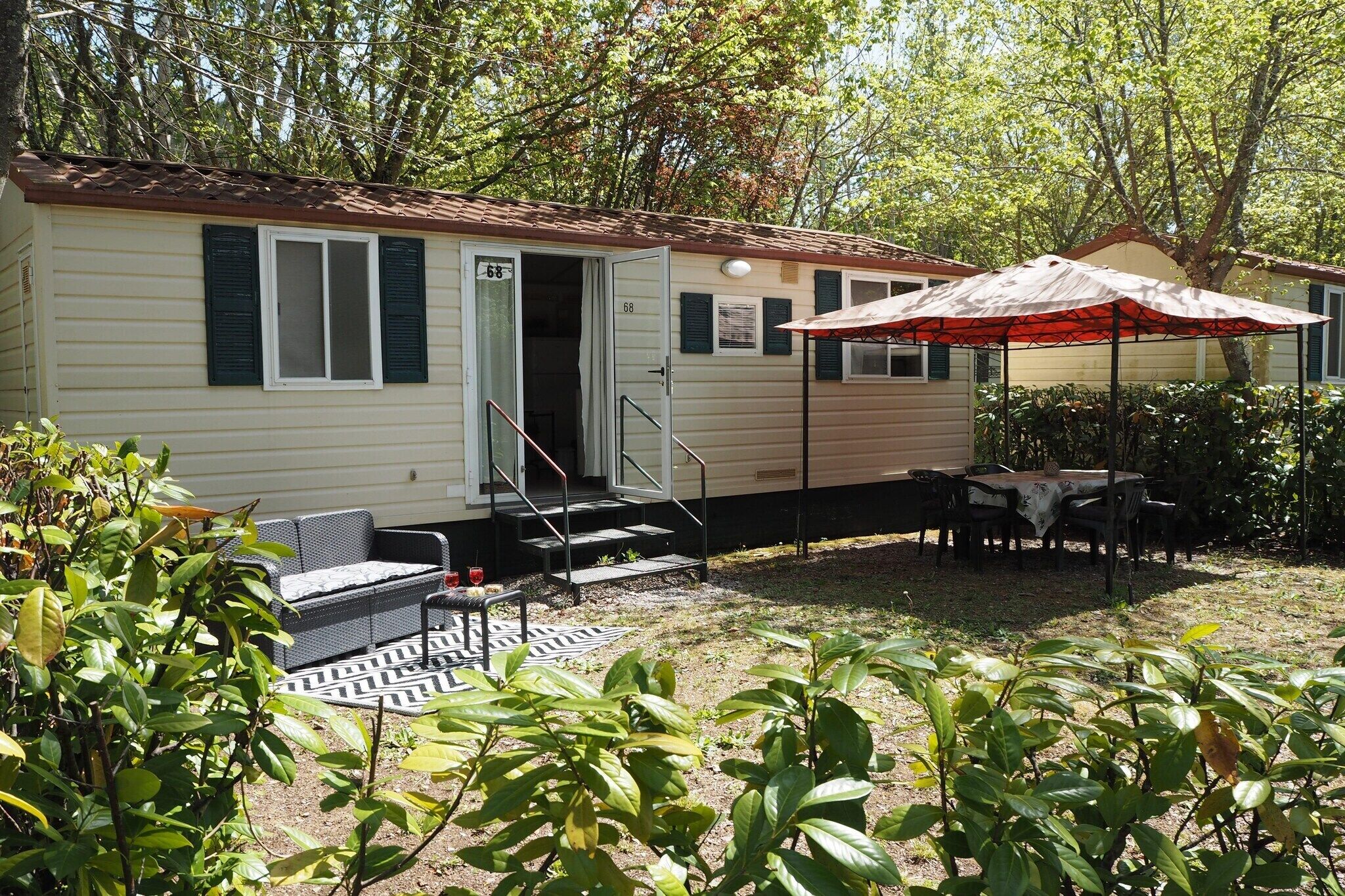 A mobile home with a patio area, outdoor furniture, and a covered table.