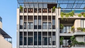 A multi-story building with a modern architectural design, featuring balconies with greenery, and storefronts with signage for 'Lô Nhi Beauty' and 'The Grace.' - THE GRACE An Thuong Hotel & Apartment (Da Nang)
