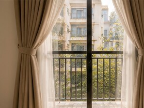 Un balcon donnant sur un immeuble et sur de la verdure.