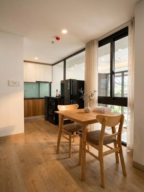 Une cuisine moderne avec un coin repas, un plancher en bois et une grande fenêtre avec des rideaux.