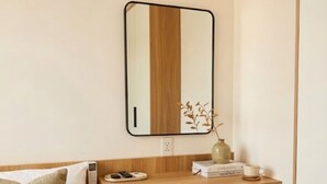 A compact hotel room with a bed, a wooden desk, a chair, a mirror, a bedside table, and a small plant. - THE GRACE An Thuong Hotel & Apartment (Da Nang)