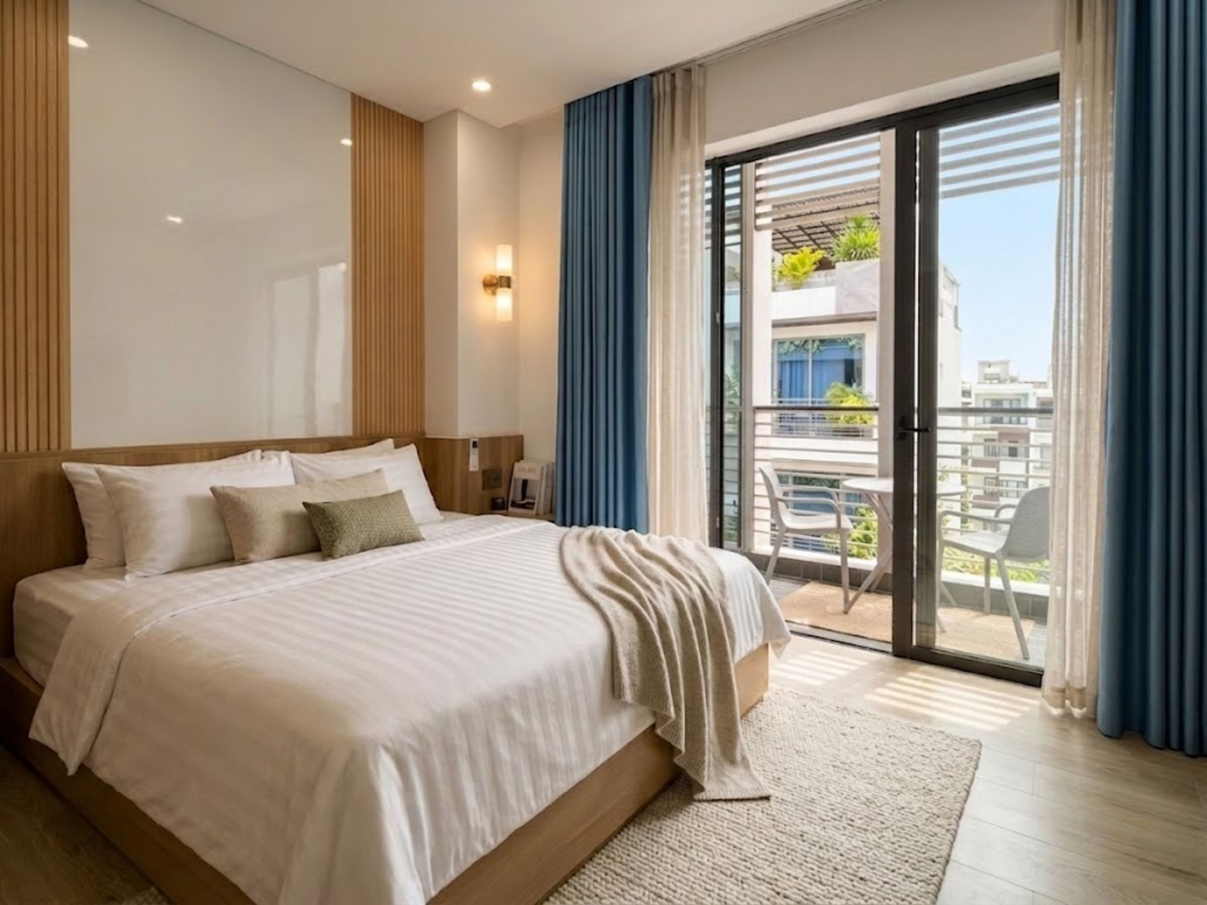Une chambre d’hôtel moderne avec un grand lit, une vue sur le balcon et une porte-fenêtre coulissante.