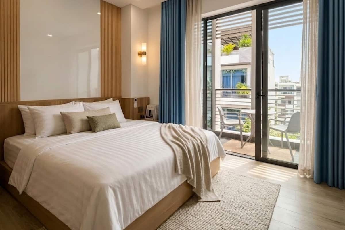 A modern hotel room with a large bed, a view of the balcony, and a sliding glass door.