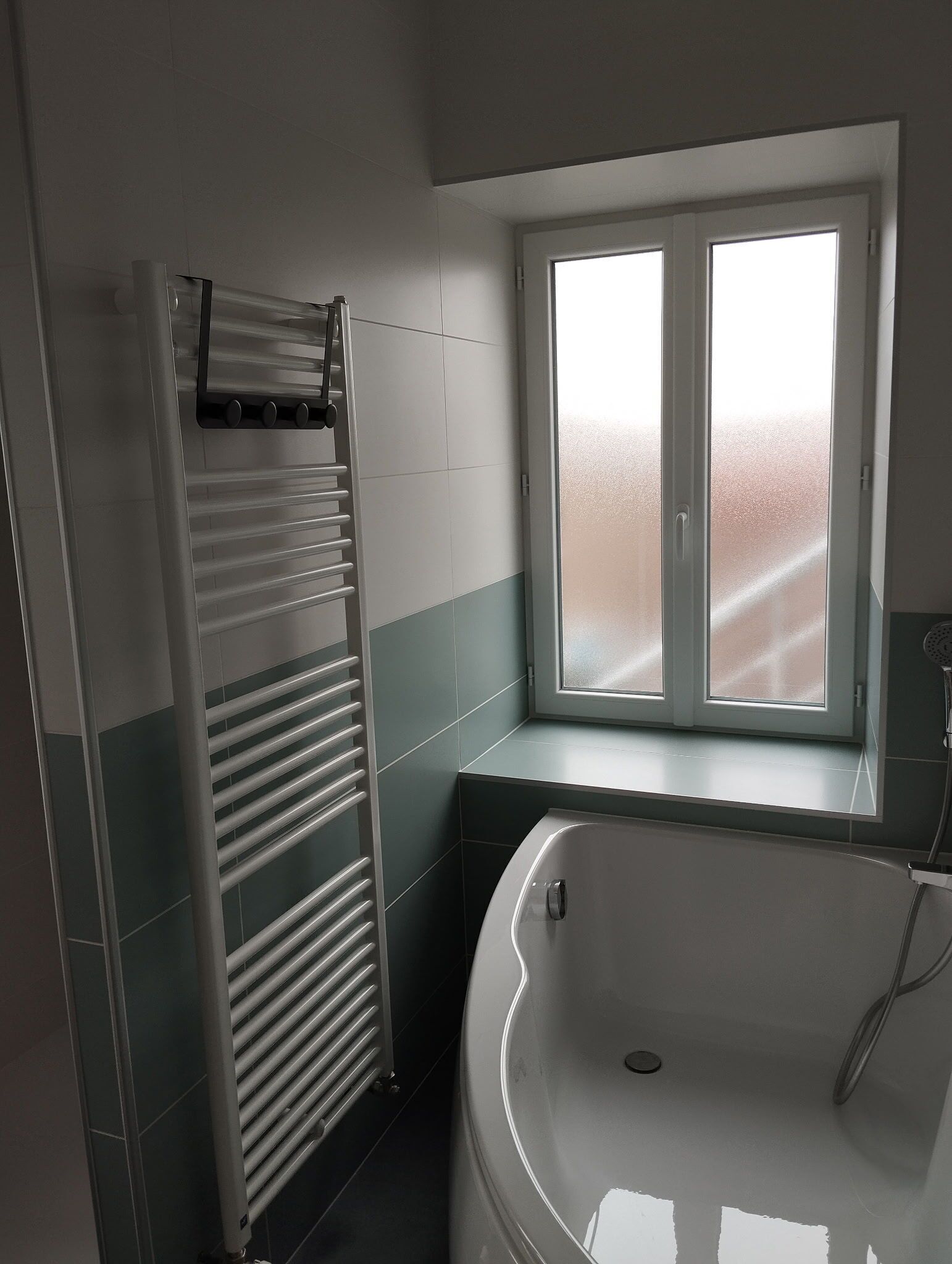 A bathroom with a bathtub, a window, and a towel rack.