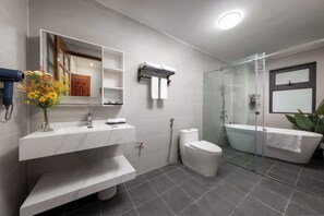 A modern bathroom with a shower, toilet, and bathtub, a vanity with a mirror, and a vase of flowers. - 500m2 Jacuzzi House 6BR West Lake/Billiard/BBQ (Hà Nội)