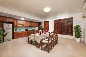 Un coin repas avec une table dressée pour quatre personnes, des meubles en bois, un réfrigérateur et une plante en pot.