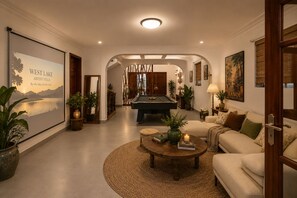 Un vaste espace de vie comprenant une table de billard, des sièges confortables et un grand tableau représentant le lac de l’Ouest.