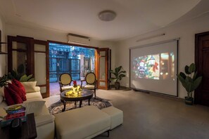 Un salon avec un canapé, une table basse et un écran de projection diffusant une scène de Noël.