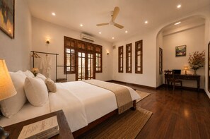 A bedroom with a bed, bedside table, lamp, and a desk with a chair.
