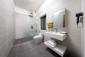 Une salle de bain moderne avec une douche à parois de verre, des toilettes, un meuble-lavabo avec un miroir et un porte-serviettes.