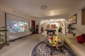 Un salon équipé d’un écran de projection, d’une table de billard et d’un canapé.