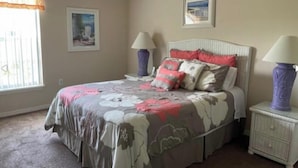 Una camera da letto con un letto, due comodini, una finestra con tende e due lampade a parete.