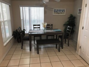 A dining area with a table, chairs, a bench, a vase with flowers, a window with blinds, and a ceiling fan. - Situated on a small gated community just a 12 minute from all Disney parks (Davenport)