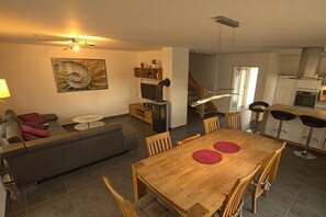 Un espace de vie moderne comprenant un coin repas, un canapé, un téléviseur, une cuisine et un escalier.