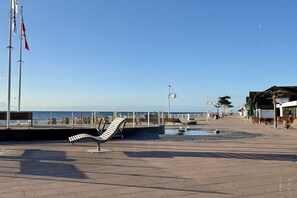 Une promenade en bord de mer, avec un banc, une rambarde et une vue sur la mer.