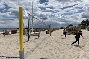 Una cancha de voleibol de playa con red, arena y gente.