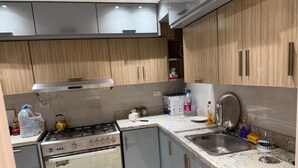 Eine Küche mit Gasherd, Backofen, Spüle und Holzschränken.