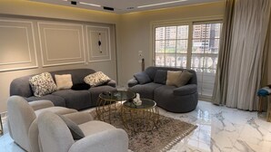 Ein modernes Wohnzimmer mit zwei Sofas, einem Couchtisch und einem großen Fenster mit Vorhängen.