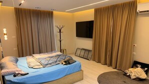 Ein modernes Schlafzimmer mit einem Bett, einem Flachbildfernseher, einem Kleiderständer und einer Heizung.