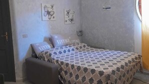 Een slaapkamer met een bed, een plafondventilator en twee decoraties aan de muur.