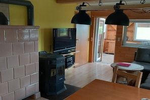 A cozy living room with a fireplace, a television, and a dining area with a table and chairs. - Holiday home with 2 bedrooms (Kurort Oybin OT Lückendorf)